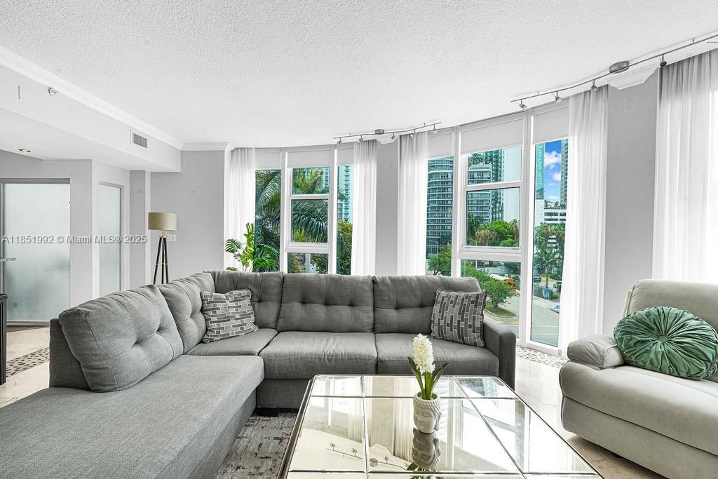 Bright and modern living area featuring floor-to-ceiling windows, abundant natural light, and open-concept design perfect for entertaining. Enjoy elegant finishes, neutral tones, and city views in this Miami high-rise condo near Biscayne Bay.