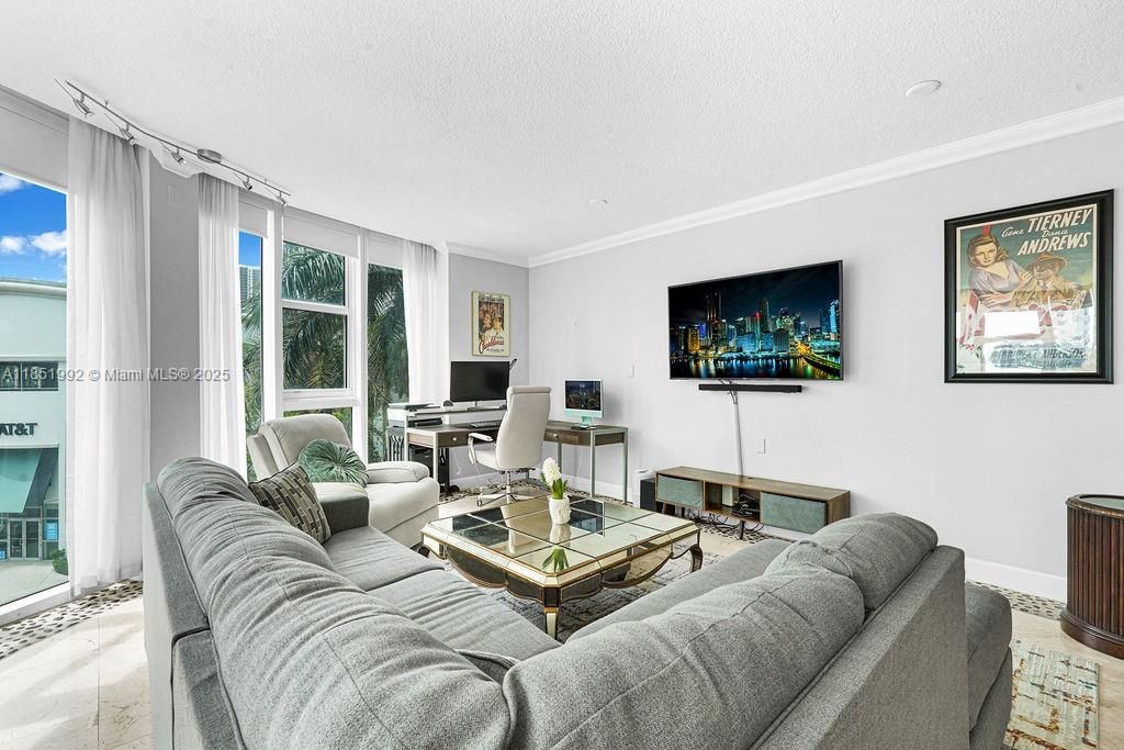 Bright and modern living area featuring floor-to-ceiling windows, abundant natural light, and open-concept design perfect for entertaining. Enjoy elegant finishes, neutral tones, and city views in this Miami high-rise condo near Biscayne Bay.