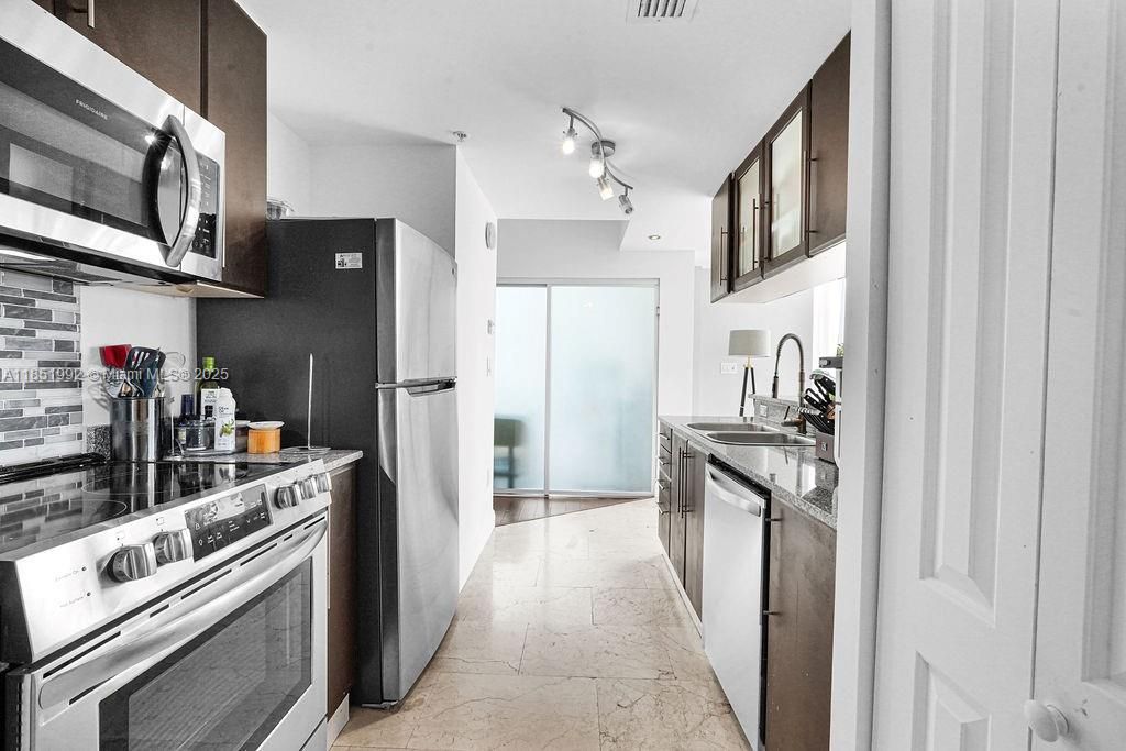 Sleek modern kitchen with stainless steel appliances, granite countertops, and contemporary cabinetry. Perfect for home chefs seeking a stylish and functional space.