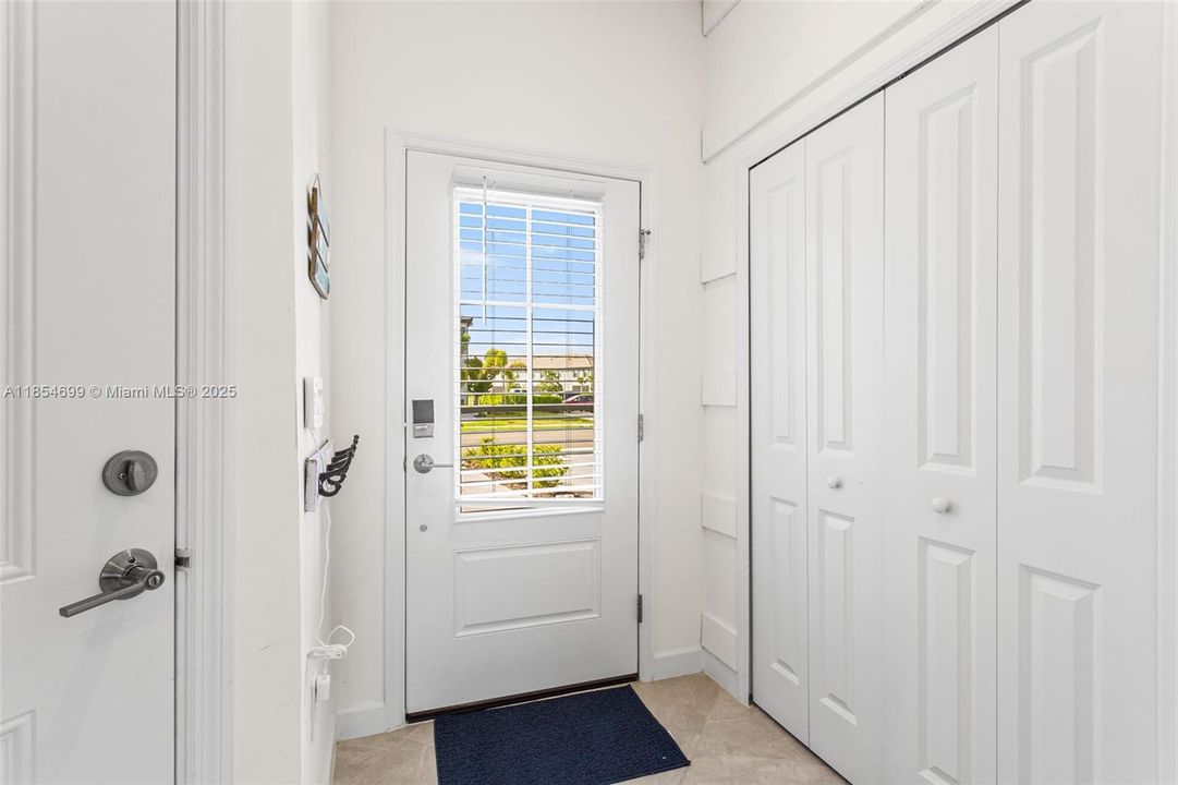 Step through decorative front door w/ glass insert, equipped w/ a keyless entry pad & security camera, into welcoming foyer featuring a coastal-inspired half bath & convenient storage closet.