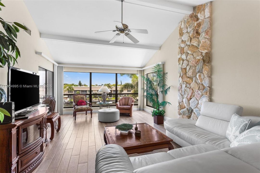 The living room with a NATURAL STONE FEATURE WALL and CAPTIVATING CANAL VIEWS is PERFECT FOR BOTH ENTERTAINING AND QUIET EVENINGS AT HOME!