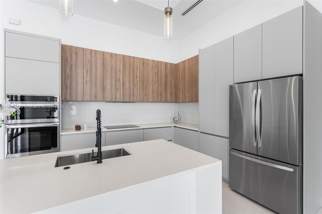 CUSTOM CABINETRY, QUARTZ COUNTERTOPS, and A LARGE SINK complete with a SLEEK MATTE BLACK FAUCET with pull-down spring spout