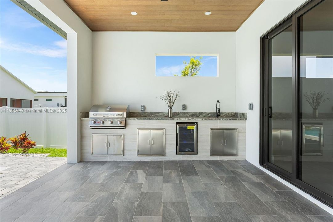 The OUTDOOR KITCHEN is READY for ENTERTAINING with a BUILT-IN BBQ GRILL, MINI FRIDGE, COMMERCIAL GRADE SINK, and plenty of counter and cabinet space for all your CULINARY NEEDS