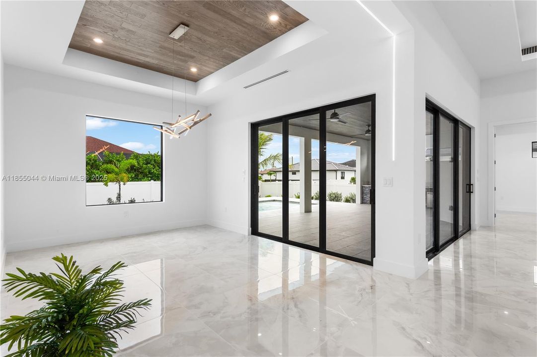 Formal dining room with flat wooden ceiling, big picture window, and sliding doors to the lanai