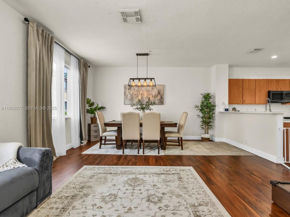 Dining Room and Living Room featuring high ceilings, laminated floors, and modern light fixtures.