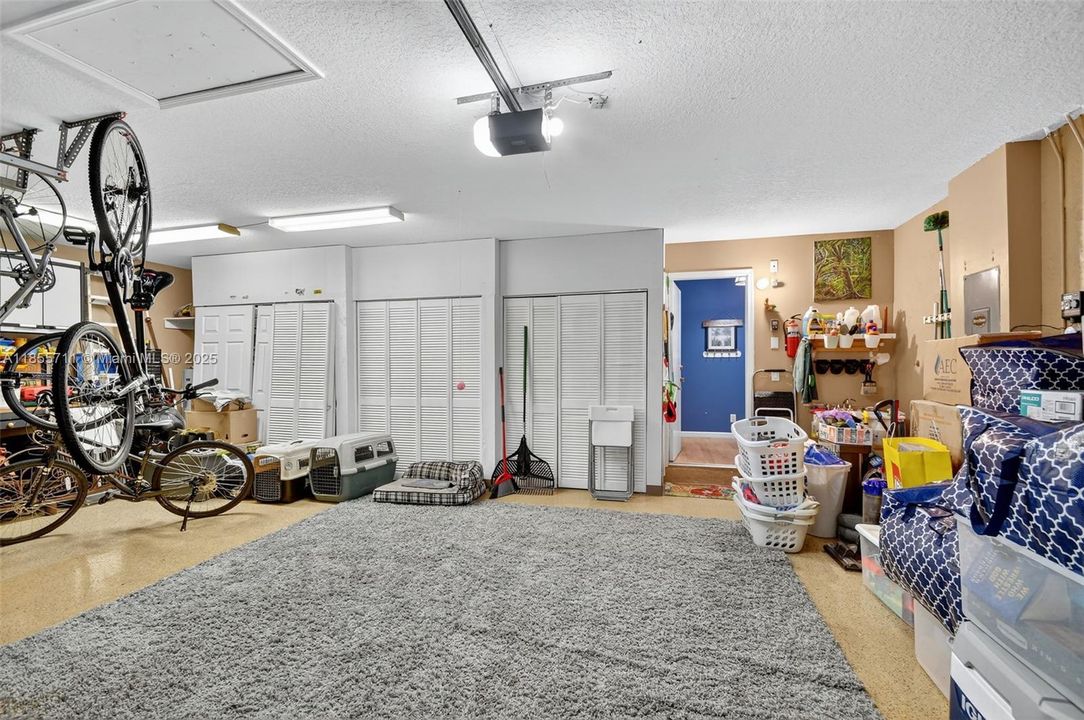 3 car garage with laundry tub sink, overhead storage, epoxy floors, and closets