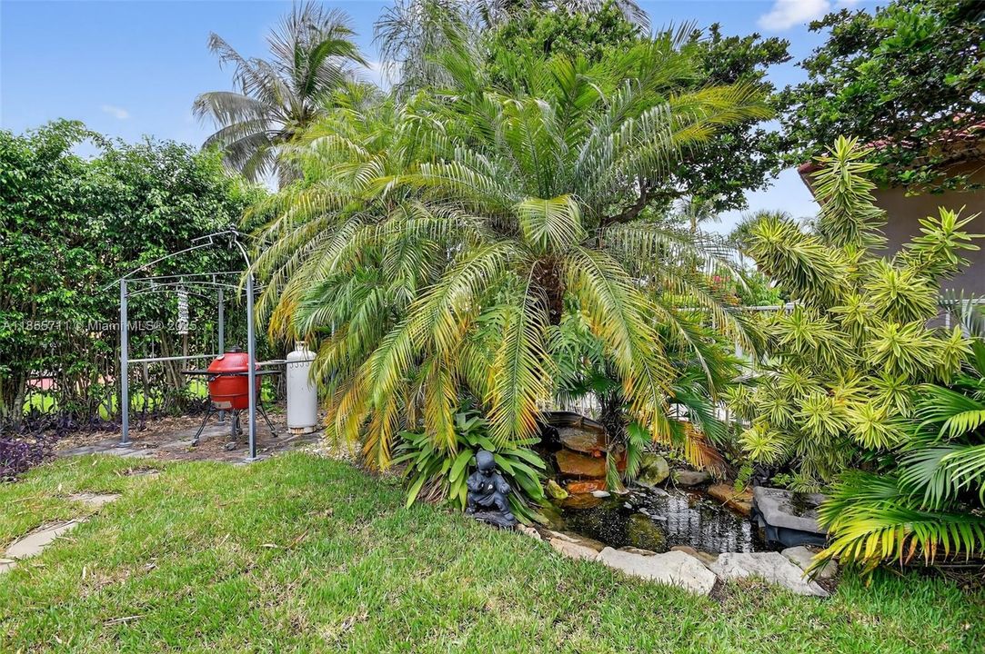 Private fenced yard with fire pit area, grilling area, mature landscaping, pond and waterfall.