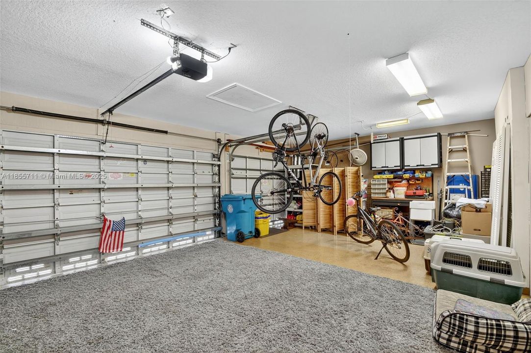 3 car garage with laundry tub sink, overhead storage, epoxy floors, and closets