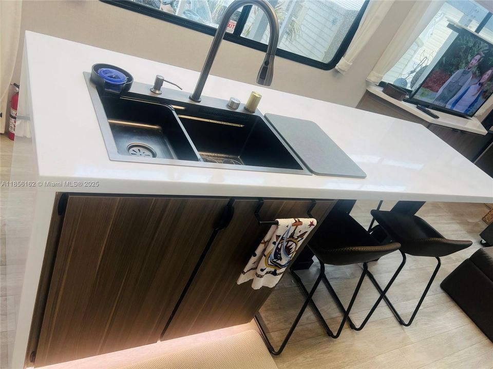 Rainfall verde kitchen sink with soap dispenser and Modern Quartz waterfall countertops with under-cabinet lighting.