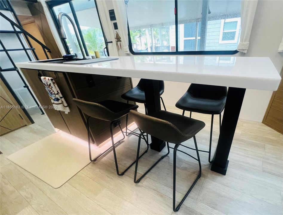 Rainfall verde kitchen sink with soap dispenser and Modern Quartz waterfall countertops with under-cabinet lighting.