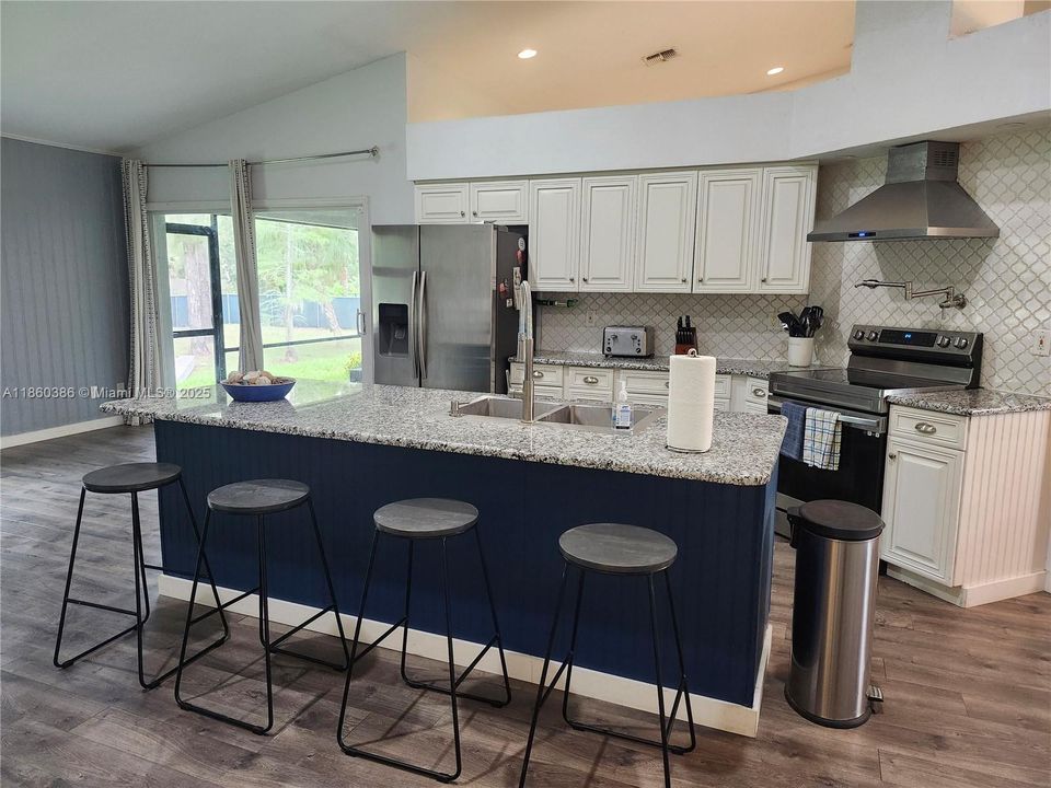 Kitchen with all stainless steel appliances and an island with seating for four.