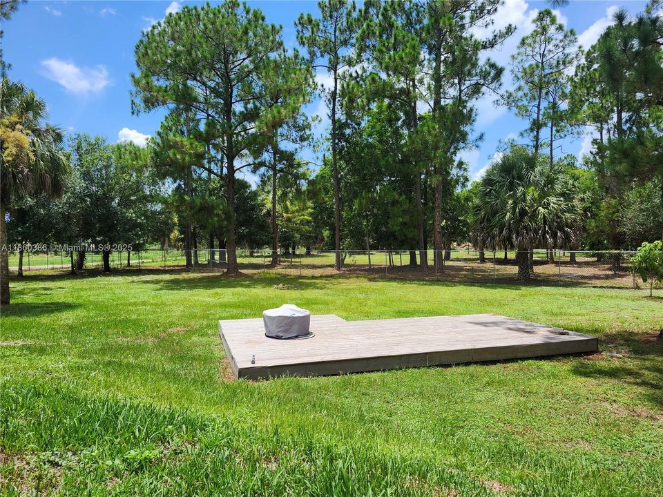 Large deck with a fire pit on the inside fenced portion of the yard.