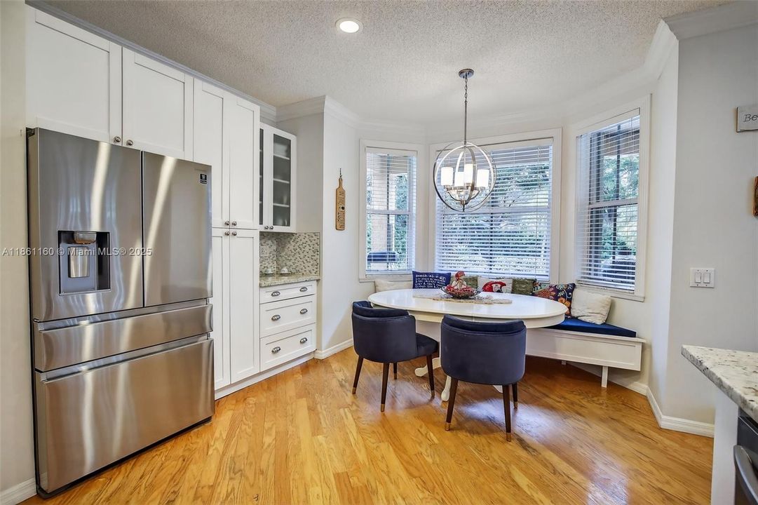 Enjoy cooking and entertaining in this stunningly remodeled kitchen. The modern, open-concept design includes a full suite of newer stainless steel appliances, timeless white cabinets, and a large peninsula perfect for meal prep and casual dining. The adjoining dining area is highlighted by a custom-made window bench, offering cozy, built-in seating that bathes in natural light.