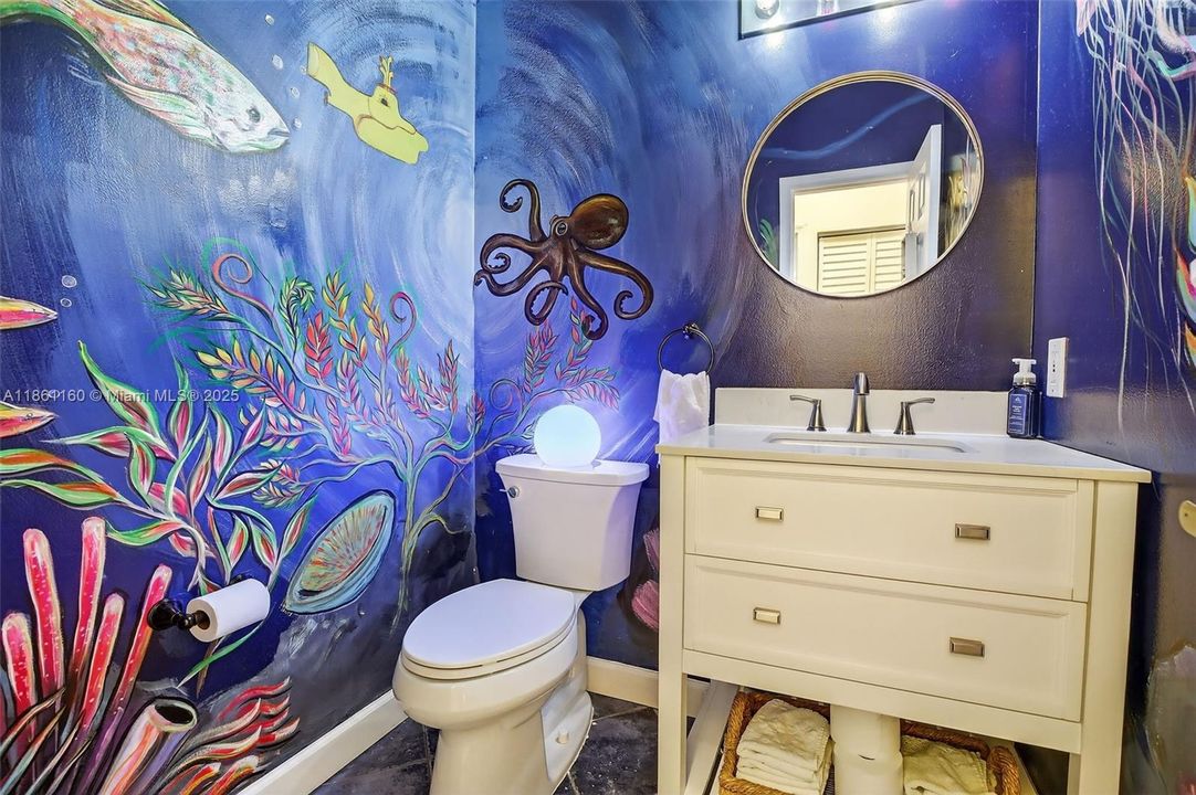 Discover a delightful surprise in the guest powder room. This space has been transformed by a custom, hand-painted oceanic mural, creating a whimsical and memorable feature. It’s a unique touch of character that makes this home truly special.