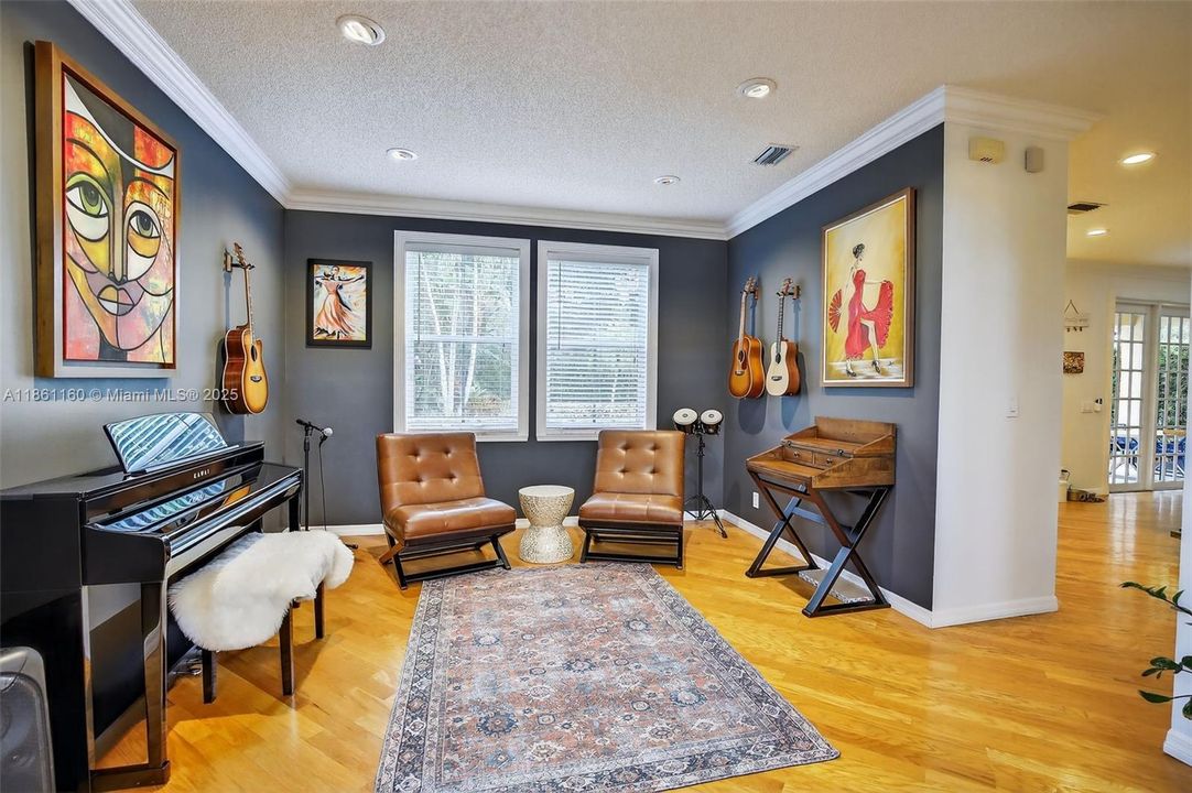 Adjacent to the main living area is the formal dining room, a beautiful space featuring rich hardwood floors and a large window for natural light. The room's generous proportions offer incredible flexibility, shown here as a chic music lounge, but ready to host your most memorable gatherings.