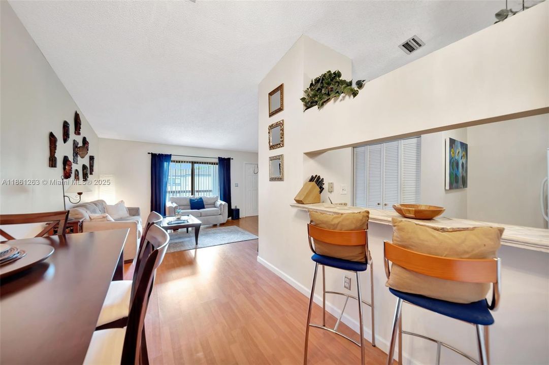 Dining area with modern pendant lighting and wood-style floors, plus a breakfast bar that opens to the kitchen — great for hosting or casual meals.