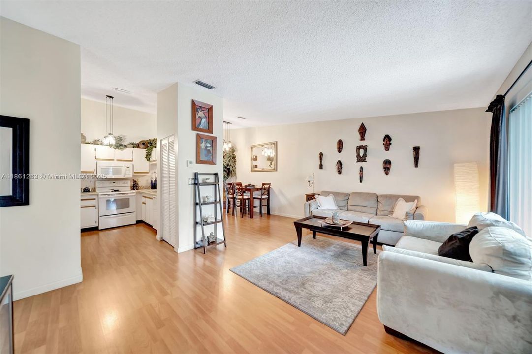 Open-concept living and dining area with warm wood-style floors, tons of natural light, and direct flow into the kitchen — perfect for relaxing or entertaining.