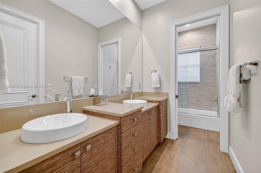 Gorgeous updated shared bathroom w/ double vanity in custom wood finish, and combination tub / shower. Designed by professional bathroom designer and contractor. Separate door for water closet / shower.