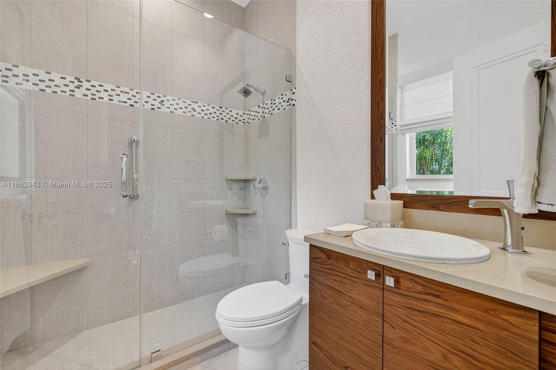Full bathroom for guests, located near the kitchen / family room. Also professionally updated by bathroom designer w/ wood grain vanity, quartz counters, tile to the ceiling and frameless shower door