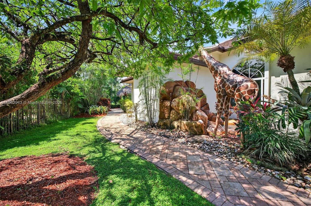 Side yard / giraffe sculpture near the royal poinciana tree (flowers in orange)