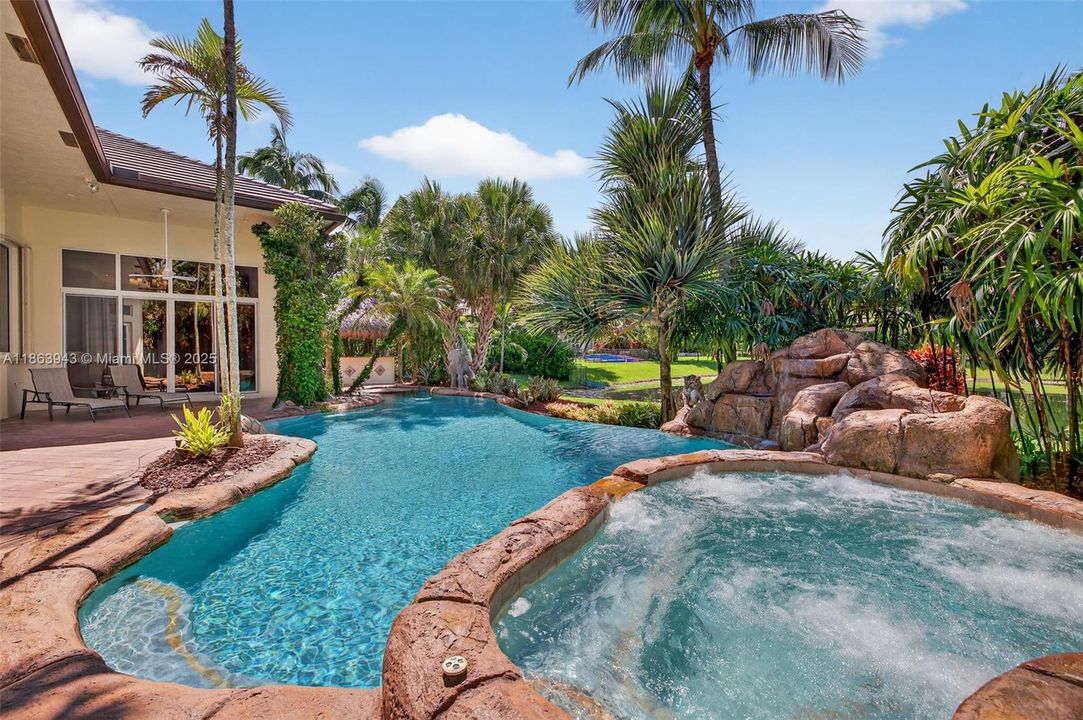 Infinity-style pool with lagoon rocks, cocktail table, spa, and life-sized sculptures.