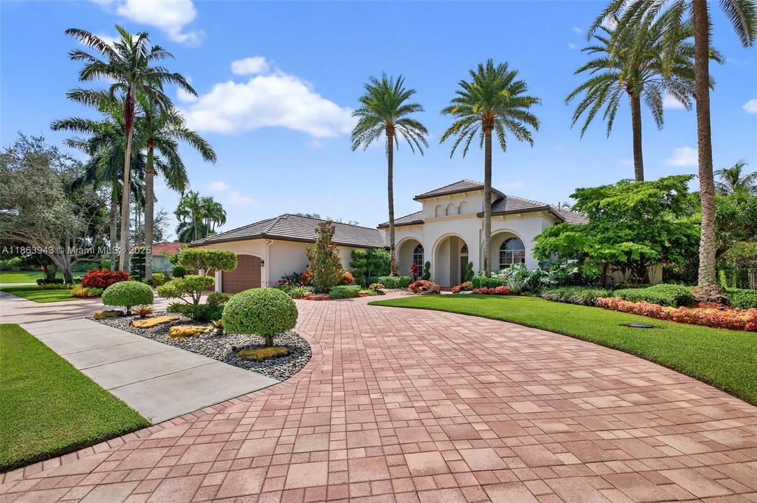 Paver circular driveway, lush landscaping, and a brand-new 2024 flat tile roof create stunning curb appeal.