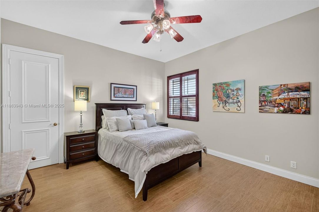Guest bedroom w/ shared bathroom to back left of photo, also has a walk in closet and overlooks the side. yard of the house / fountain. Porcelain wood look flooring.