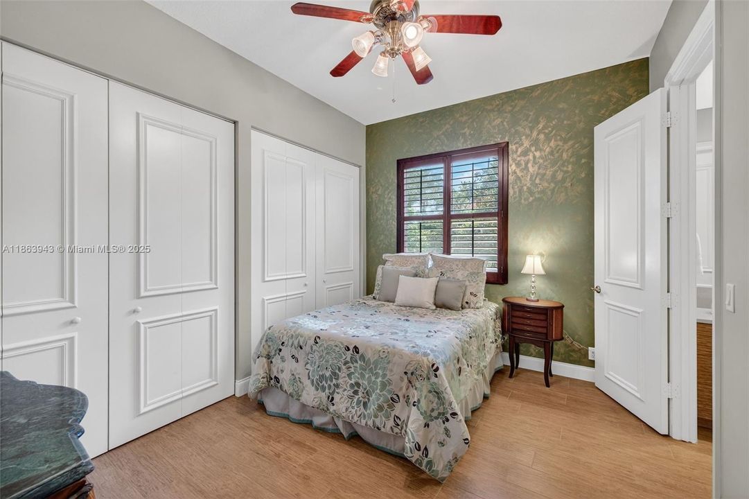 Guest bedroom w/ shared bathroom, also has a wall to wall closet and overlooks the side. yard of the house / fountain. Porcelain wood look flooring.