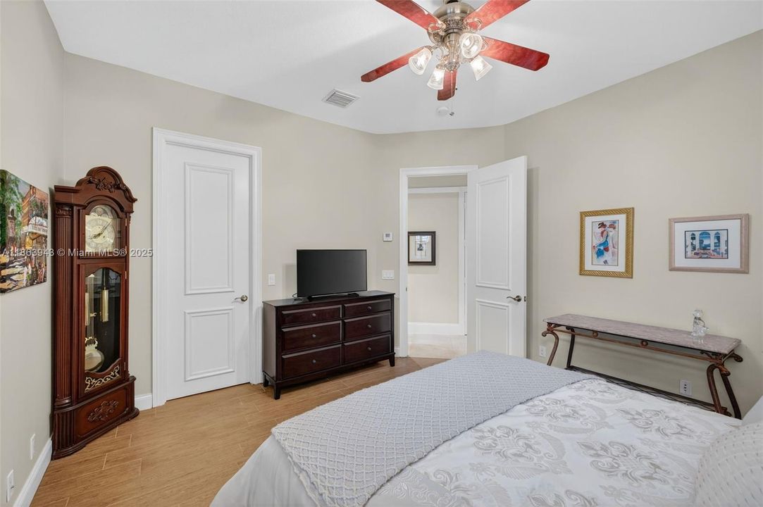 Guest bedroom w/ shared bathroom to back left of photo, also has a walk in closet and overlooks the side. yard of the house / fountain. Porcelain wood look flooring.