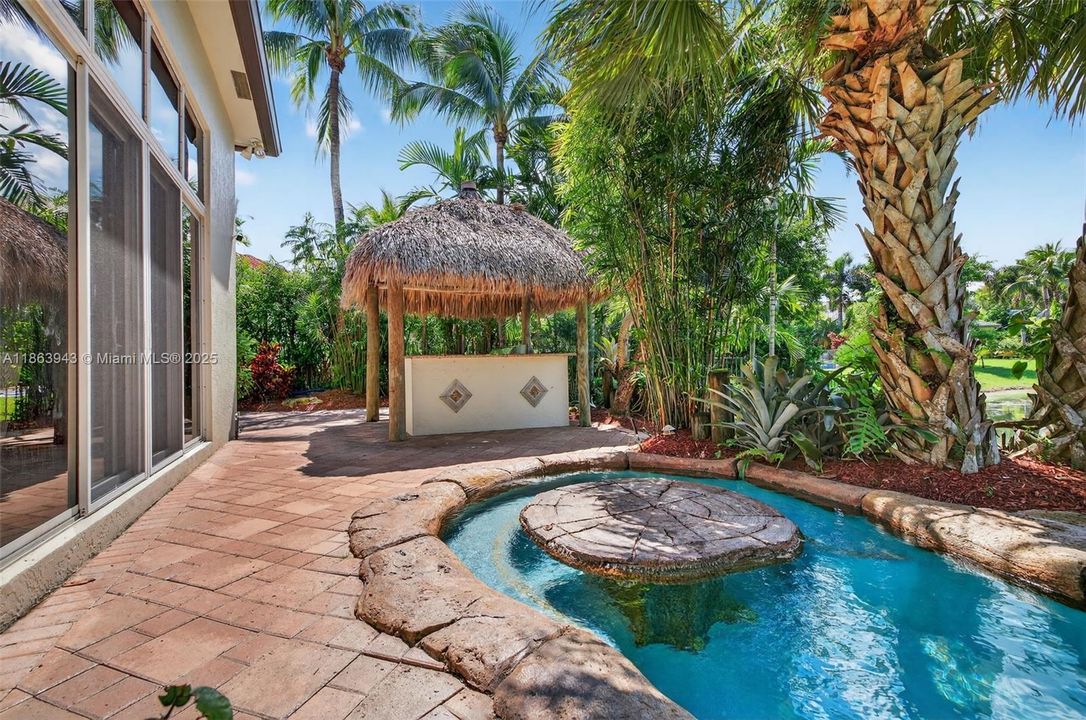 Tiki bar with Lynx grill, lush landscaping, and water features complete your backyard oasis.