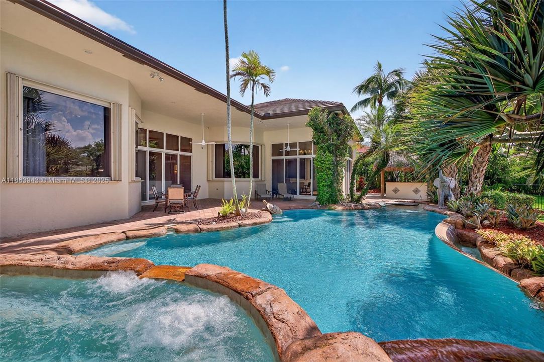 Infinity-style pool with lagoon rocks, cocktail table, spa, and life-sized sculptures.