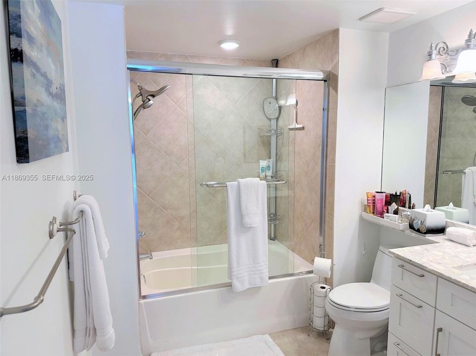 Upgraded bathroom, new countertop, cabinetry and fixtures with glass shower door.