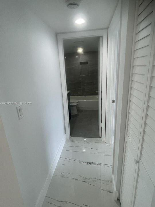 hallway to guest bathroom with tub