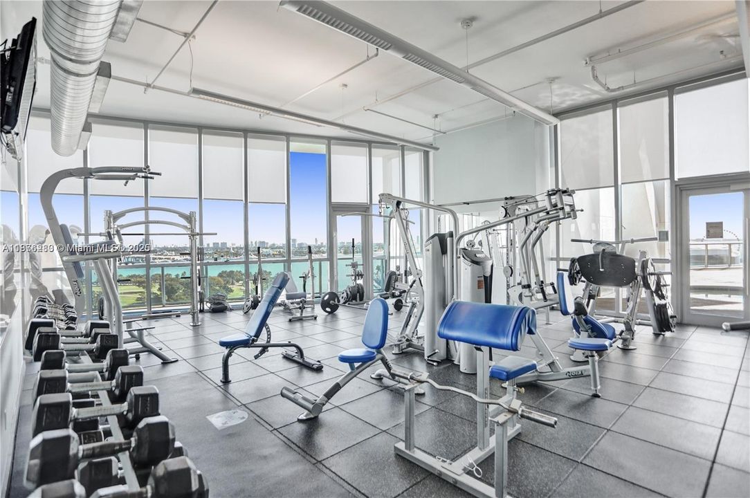 Fully equipped gym with premium strength and cardio machines, all surrounded by floor-to-ceiling windows and inspiring water views.