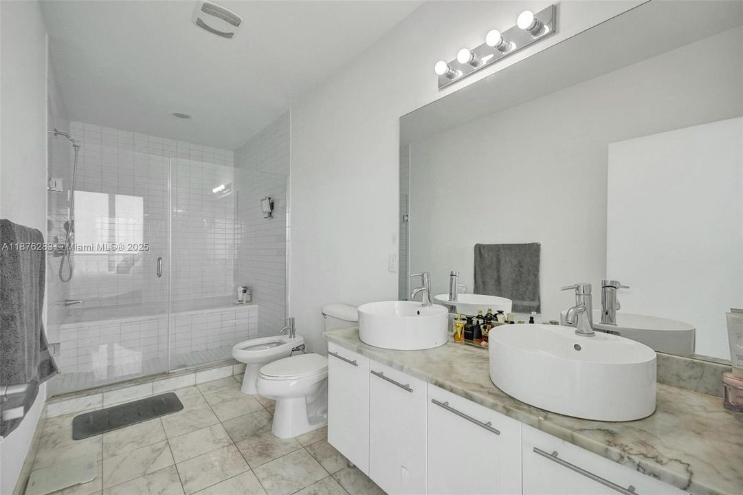 Large spa-style bathroom with double vanities, walk-in shower, and marble finishes.