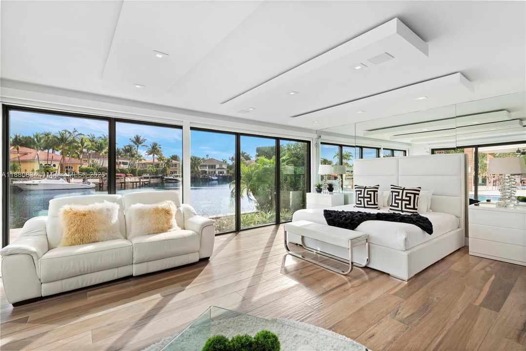 Bright bedroom with light wood floors and scenic waterfront vista.