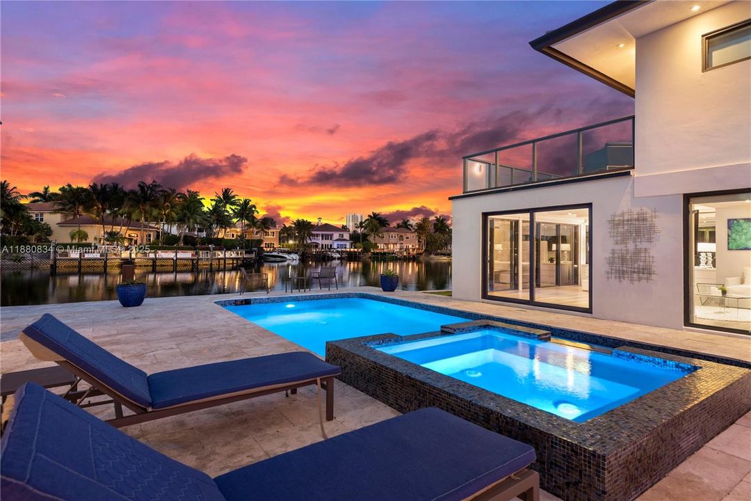 Luxurious pool area with illuminated home at dusk.
