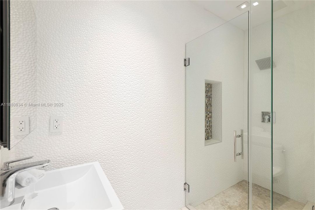 All-white bathroom with a modern walk-in glass shower.