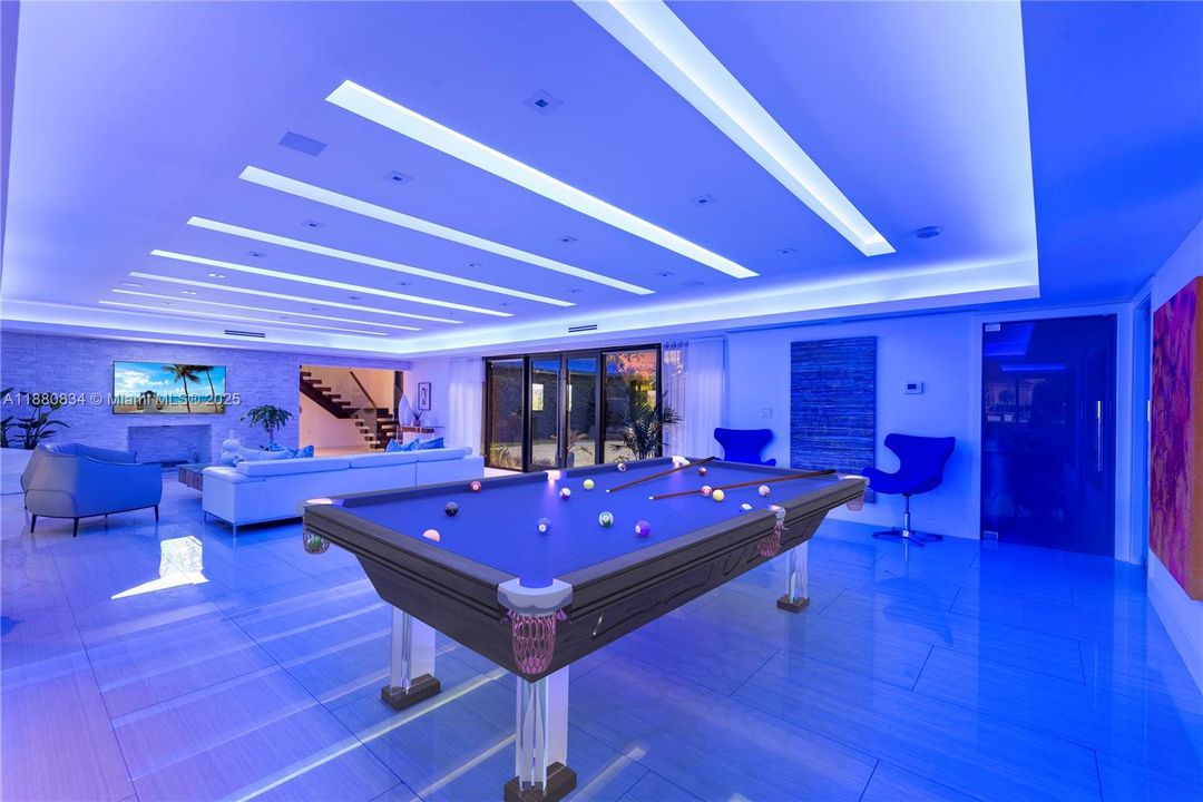 Sleek entertainment area with a pool table under cool blue lights.