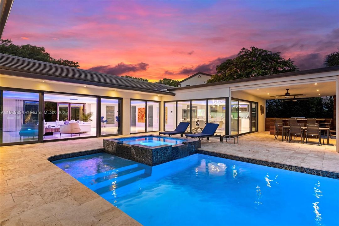 Pool/Jacuzzi with water features with an infinity edge under a vibrant sunset.
