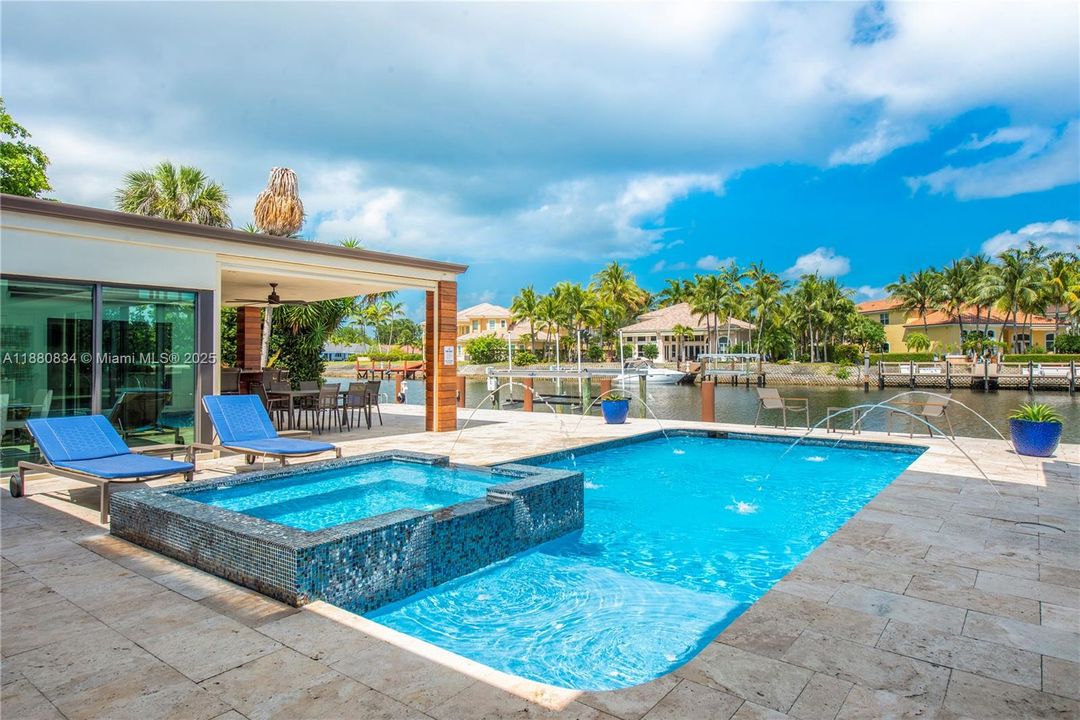 Inviting blue swimming pool and integrated hot tub by the water.