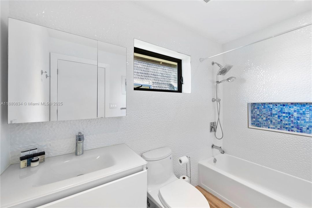 White bathroom featuring a blue mosaic tile shower.