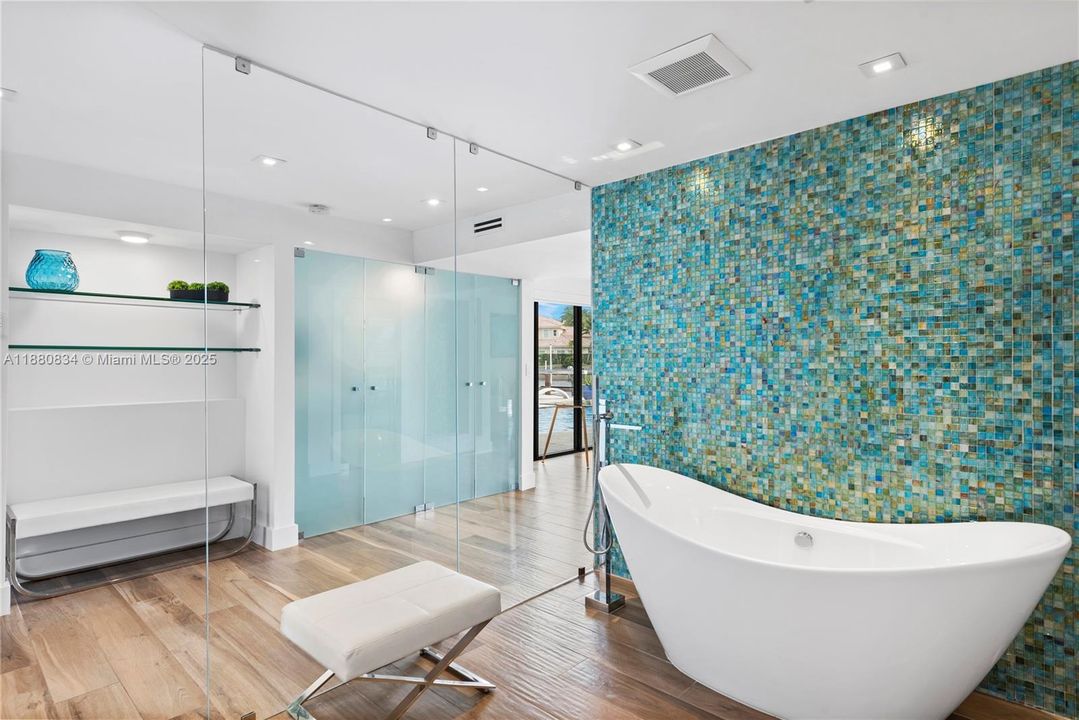 Luxurious bathroom with a freestanding tub and shimmering mosaic wall.