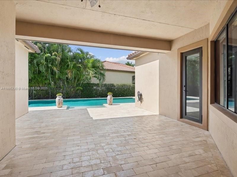 Spacious covered terrace designed for lounging and dining, framed by poolside scenery.