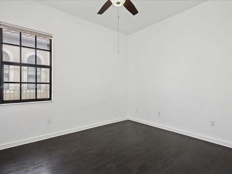 Beautifully appointed Bedroom #2 with timeless dark hardwood floors matching the home’s refined design