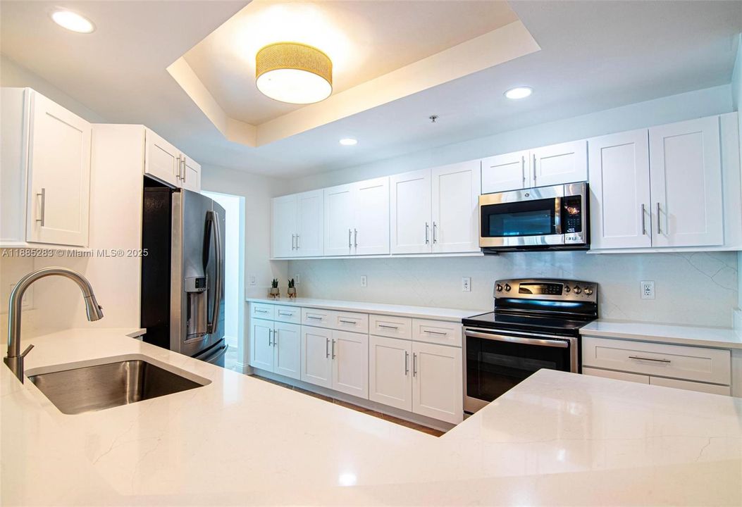 HUGE KITCHEN is equipped with QUARTZ countertops and backsplash, BRAND NEW CUSTOM-MADE WHITE SHAKERS CABINETS, newer STAINLESS-STEEL GE PROFILE APPLIANCES & breakfast or cocktail SITTING BAR AREA.