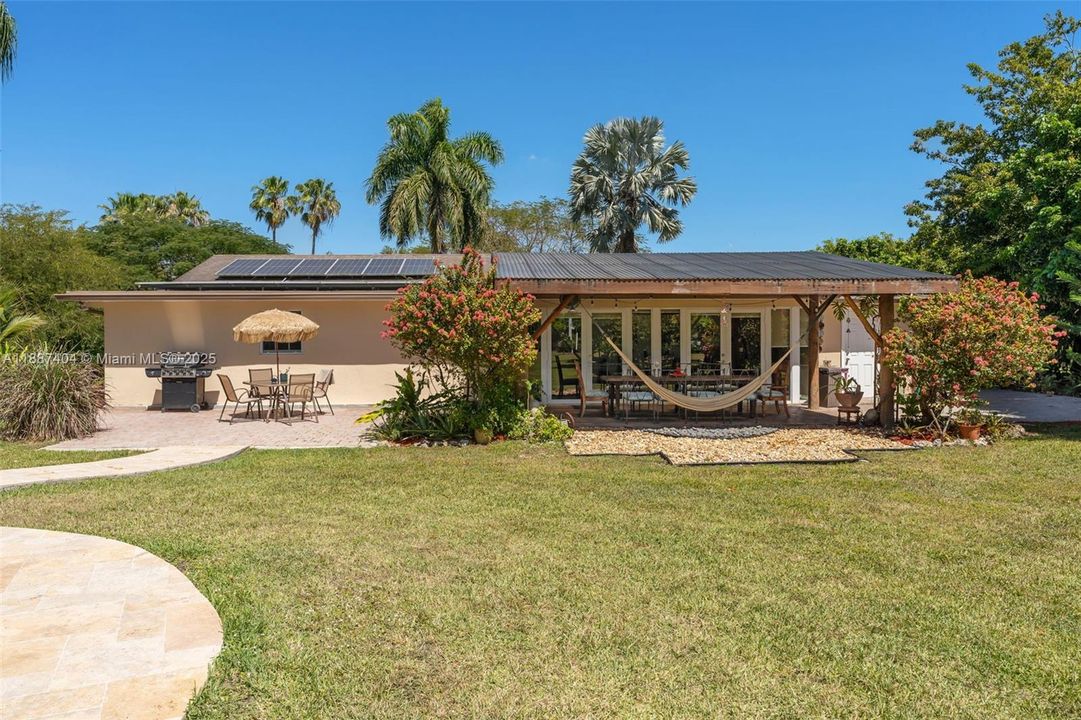 rear view of the home w/ covered patio located off Florida Room features custom wood columns ideal for hanging hammock.. in addition the property has solar!