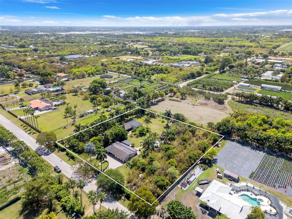 Front aerial view and a consistent neighborhood of Agri properties. LA CHAKANA..FOR BEST VIEWING Click ON ALL PHOTOS TO ENLARGE.AN Organic Agricultural retreat w/ 4/4 home, Artisan studio, Pool & spa, 2 tiki huts, barn, assorted fruit grove & gardens ON 2+ ACRES in Redland.