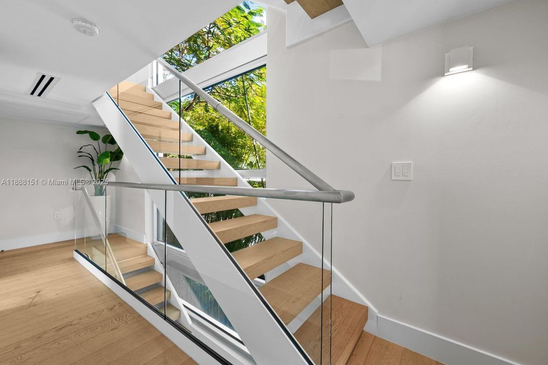 Sleek architectural staircase with modern railing — statement feature connecting both levels with open-air flow.