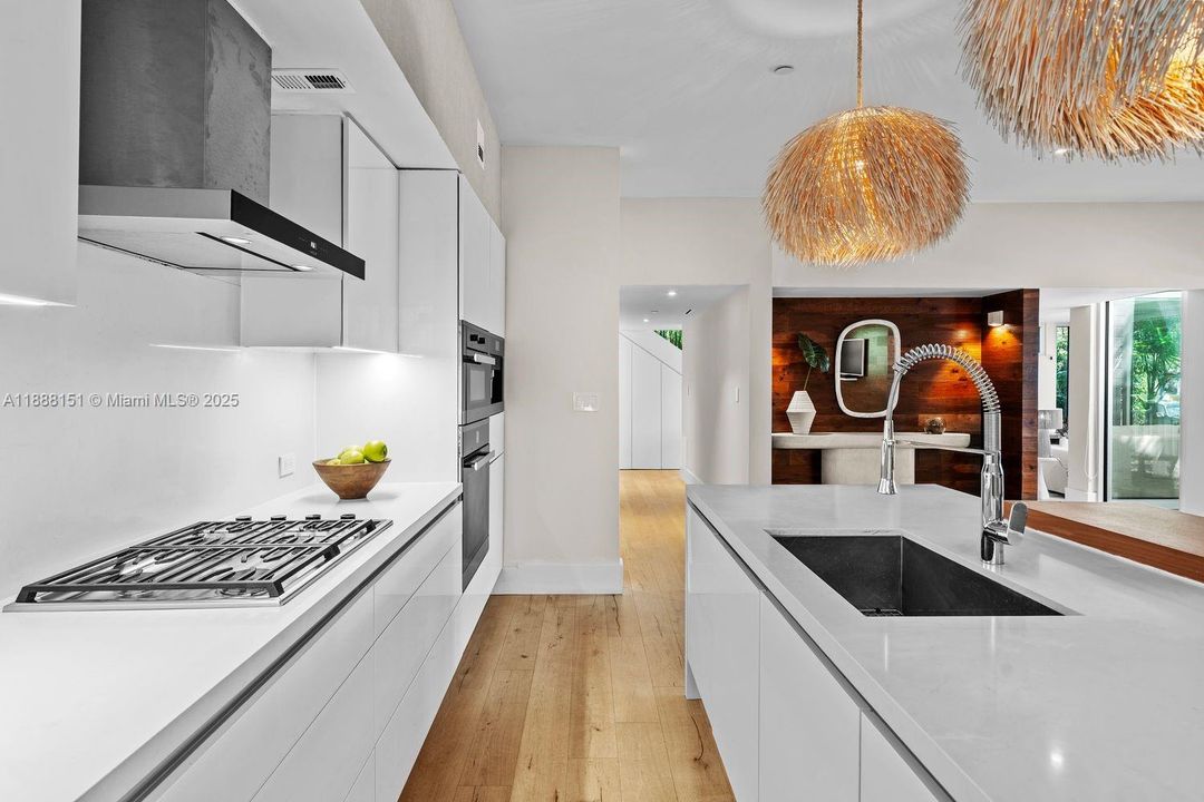 Bright chef’s kitchen featuring built-in oven, sleek backsplash, and spacious island ideal for cooking and social gatherings.